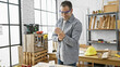© Krakenimages.com - Hispanic man grimacing in pain holding wrist in a well-equipped carpentry workshop indoors