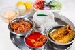 Bengali non vegetarian food thali comprising of plain white rice with spicy chicken curry, prawn and fish dishes, along with dessert and salad.