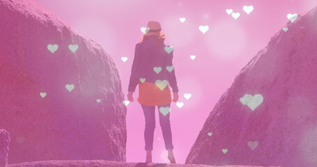 Poster - Image of glowing spots and hearts over caucasian woman standing on rock