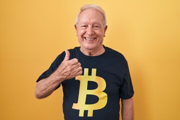 Sticker - Senior man with grey hair wearing bitcoin t shirt doing happy thumbs up gesture with hand. approving expression looking at the camera showing success.