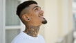 © Krakenimages.com - Cheerful young latin man, tattooed and confident, smiling as he looks up at the sky, standing on an urban street.
