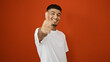 © Krakenimages.com - Confident young latin man flashing a thumbs up gesture, cool and positive, smiling over an isolated red background, expressing joy and fun in his casual lifestyle, portrait of a handsome adult