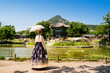 Seoul, South Korea. Hanbok wearing woman. Gyeongbokgung palace park garden. Korean dress tradition. Hyangwonjeong Pavilion in the background. Tourist in Gyeongbok. Traditional culture tour and travel.