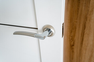 Sticker - A closeup of a varnished hardwood door handle fixture on a white door