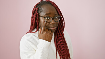 Canvas Print - Thoughtful african woman with braids and glasses posing over a pink background