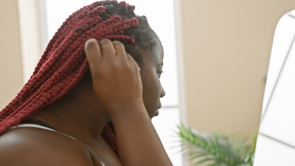 Poster - An african american woman with red braids in a pensive mood inside a well-lit room, portraying a sense of calm and introspection.