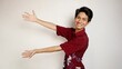 Excited handsome Asian young man wearing a batik shirt and smiling kindly pointing to the side with both hands on an isolated white background