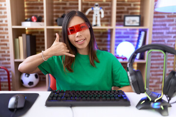 Wall Mural - Middle age chinese woman wearing virtual reality glasses smiling doing phone gesture with hand and fingers like talking on the telephone. communicating concepts.