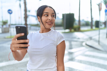 Wall Mural - Young arab woman smiling confident using smartphone at street