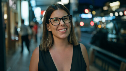 Wall Mural - Laughing out loud, a confident beautiful hispanic woman wearing glasses stands joyfully on a street in kyoto, light-filled japanese city at night, looking positively radiant and carefree