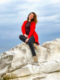 Fototapeta Sypialnia - girl in a red jacket on the seashore