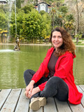 Fototapeta Sypialnia - Portrait of beautiful young woman wearing red jacket outdoors