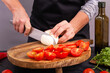 View of the process of preparing fresh vegetable salad with mozzarella cheese on a wooden chopping board, closeup with selective focus