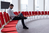 Fototapeta Morze - Portrait d'un homme qui travaille seul, assis dans une salle de réunion ou une salle de conférence avec un ordinateur portable. C'est un homme d'affaires ou un salarié d'une entreprise
