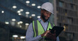 © peopleimages.com - Black man, engineer and city building with tablet for online inspection or safety protocol, architecture or late night. Male person, hardhat and construction project with deadline, internet or urban