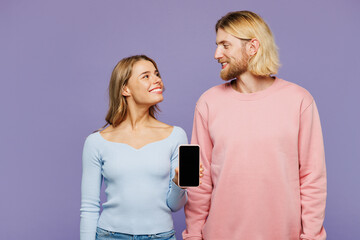 Wall Mural - Young couple two friends family man woman wear pink blue casual clothes together hold in hand use mobile cell phone with blank screen workspace area isolated on pastel plain light purple background.