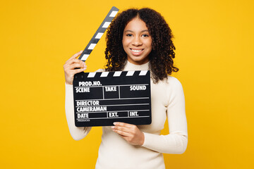 Wall Mural - Little kid teen girl of African American ethnicity wear white casual clothes hold in hand classic black film making clapperboard isolated on plain yellow background studio Childhood lifestyle concept