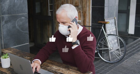 Poster - Image of like icons over caucasian man wearing face mask, using smartphone and laptop