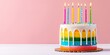 Colorful layered birthday cake with dripping icing and lit candles on a pink background.
