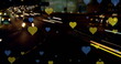 Image of yellow and blue hearts floating over night cityscape