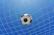 © Igor Link - Soccer ball in soccer goal net in a big stadium isolated on blue sky. soccer net.