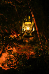 A lamp hanging in the rural, public park in the dark. Close-up of a lamp with black background. Lighting in the dark.