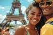 A young woman and man are smiling for the camera in front of the Eiffel Tower. The woman is wearing a yellow shirt and a green and yellow headband