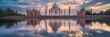Iconic view of the Taj Mahal reflected in the Yamuna River against a backdrop of a sunset sky, showing the monument's grandeur and symmetry