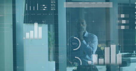 Image of financial data and graphs over thoughtful african american businessman in office