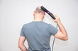 Bald Caucasian man using an electric hair comb, rear view