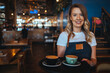 Coffee Business owner Concept - attractive young beautiful  barista with apron in coffee shop. Happy waitress at a cafe serving a cup of coffee. Small business owner