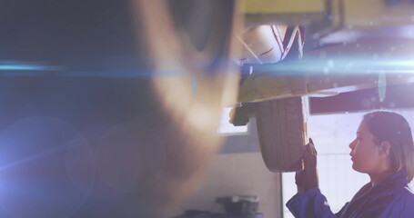 Poster - Image of glowing light over biracial woman working in car workshop