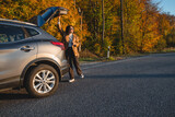 Fototapeta Na drzwi - a smiling man with a backpack on his back closes the trunk of the car in autumn season. copy space