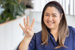 Happy smiling middle aged asian woman pointing up 4 fingers, four points, number four, forth point