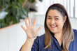 Happy smiling middle aged asian woman pointing up 5 fingers, five points, number five, fifth point