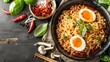   A bowl of noodles topped with hard-boiled eggs Spices nearby on a black surface