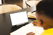 African American boy wearing yellow shirt is drawing next to a tablet at home with copy space