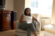 Mature biracial woman relaxing in bright living room at home