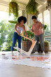 Biracial mother and adult daughter are painting furniture together at home for an upcycling project