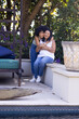 Biracial mother and adult daughter are embracing on a garden bench at home in the garden