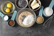Raw dough with chocolate chips in bowl and ingredients on grey table, flat lay