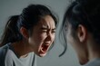 Angry young adult asian woman yelling versus her husband. Man and woman shouting at each other over dark studio background. Argue husband has expression of disappointment and upset with wife