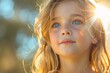 A young girl with backlit golden hair and blue eyes looking thoughtfully into the distance