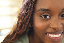 African American Young Woman With Braided Hair Is Smiling At Home