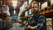 A warehouse worker looks into the camera. A man in a checkered shirt works in a logistics center. Warehouse with high racks. A man with a beard.
