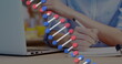 Image of dna strand spinning over businesswoman using laptop