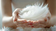 © JMarques - Close-up of a woman with white feathers in her hand. Concept of quality textile, soft feathers, clean and comfortable bedding.