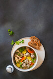 Fototapeta Dinusie - White bean beef meatball soup with  seasonal vegetables on grey background, directly abiove