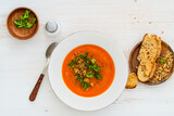 Fototapeta Dinusie - Squash soup with bread crumbs, parsley served with crusty bread on white wood, high angle view