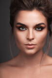 Fototapeta Dinusie - Portrait of woman with striking eye makeup and flawless skin